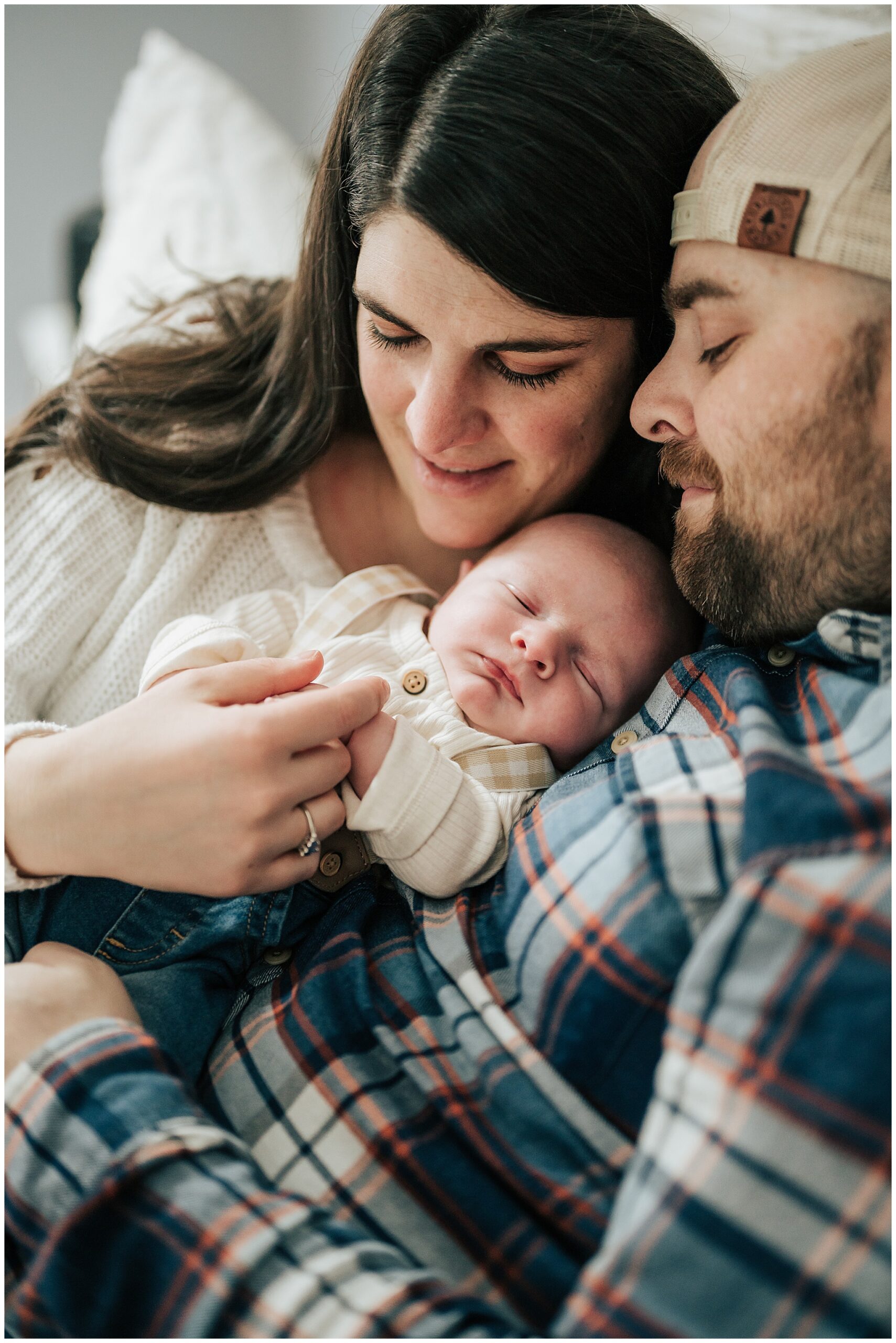 A professional photo showing how it felt at the very beginning as new parents treasure those newborn moments. A young mother and father are holding their newborn little baby boy and smiling.