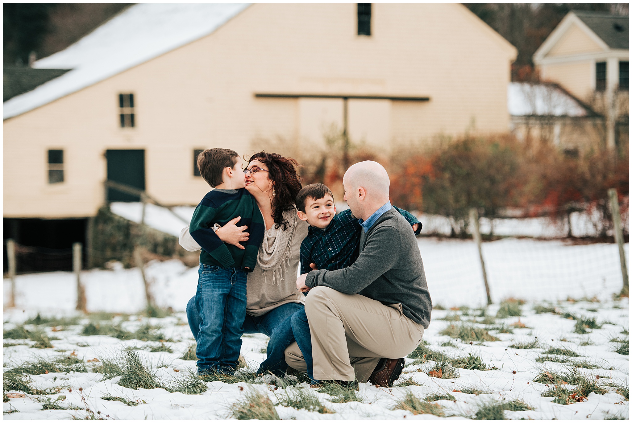 A family (father, mother, and two young sons) hugging each other affectionately during their family photography session outside of Boston.